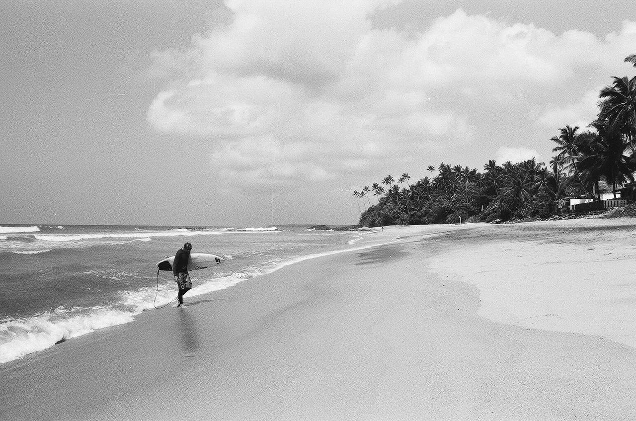 Тони с доской для серфа на пляже